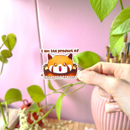 Close-up of a hand peeling and placing the red panda sticker onto a smooth surface near a plant to show size and flexibility. The matte laminated surface and clean die cut edges highlight the durable finish. This funny therapy humor decal applies easily to journals, planners, laptops and water bottles as a playful, relatable mental health joke.