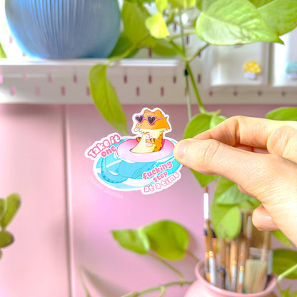 Close-up of a hand peeling and placing the pink bearded dragon sticker onto a smooth surface near a plant to show size and flexibility. The matte laminated surface and clean die cut edges highlight the durable finish. This cute lizard decal applies easily to journals, planners, laptops and water bottles, making it a fun everyday self care and motivational reminder.