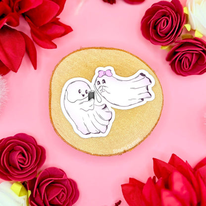 Kawaii ghost couple stickers sitting side by side sharing headphones and listening to music together, styled on cork with roses and soft pink decor for a calm, cozy vibe. The tiny ghosts lean close like best friends enjoying a quiet moment, adding a wholesome spooky cute feel that blends Halloween charm with Valentine sweetness. Handmade matte laminated and waterproof, these durable stickers are great for planners, laptops, journals, water bottles and cute stationery gifts.