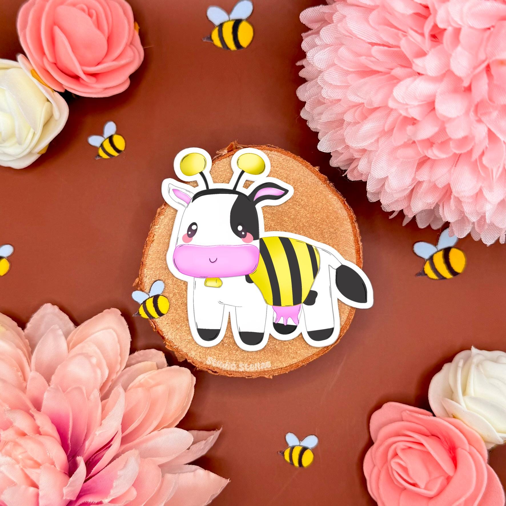 Close up of the second bee cow sticker on a warm brown floral background, featuring the side-view cow in a bumblebee outfit with wings and striped body. The photo highlights vibrant print, matte lamination, and crisp die cut shape, making it easy to see details for decorating a planner, journal, laptop, phone case, or water bottle. A cute MySims inspired cozy game sticker for farm vibe lovers and kawaii stationery fans.