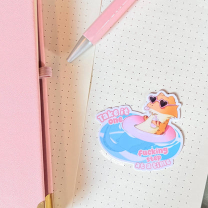 The bearded dragon sticker displayed on a notebook or wall surface in a cozy pastel workspace, showing how the design looks when used for everyday decoration. The floating pink lizard and funny quote add personality and humor to planners and journals. This mental health reminder sticker works great for stationery lovers, students and anyone who enjoys cute reptile art.