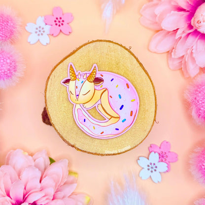 Cute dragon sticker styled in a soft pastel flat lay with pink flowers and warm cork textures. The tiny frosted sugar cookie dragon curls up in pink icing like a pastry, blending kawaii dragon art with cozy fantasy bakery vibes. This handmade matte laminated vinyl decal looks sweet and magical, perfect for decorating journals, planners, laptops and water bottles or gifting to dessert and stationery lovers.