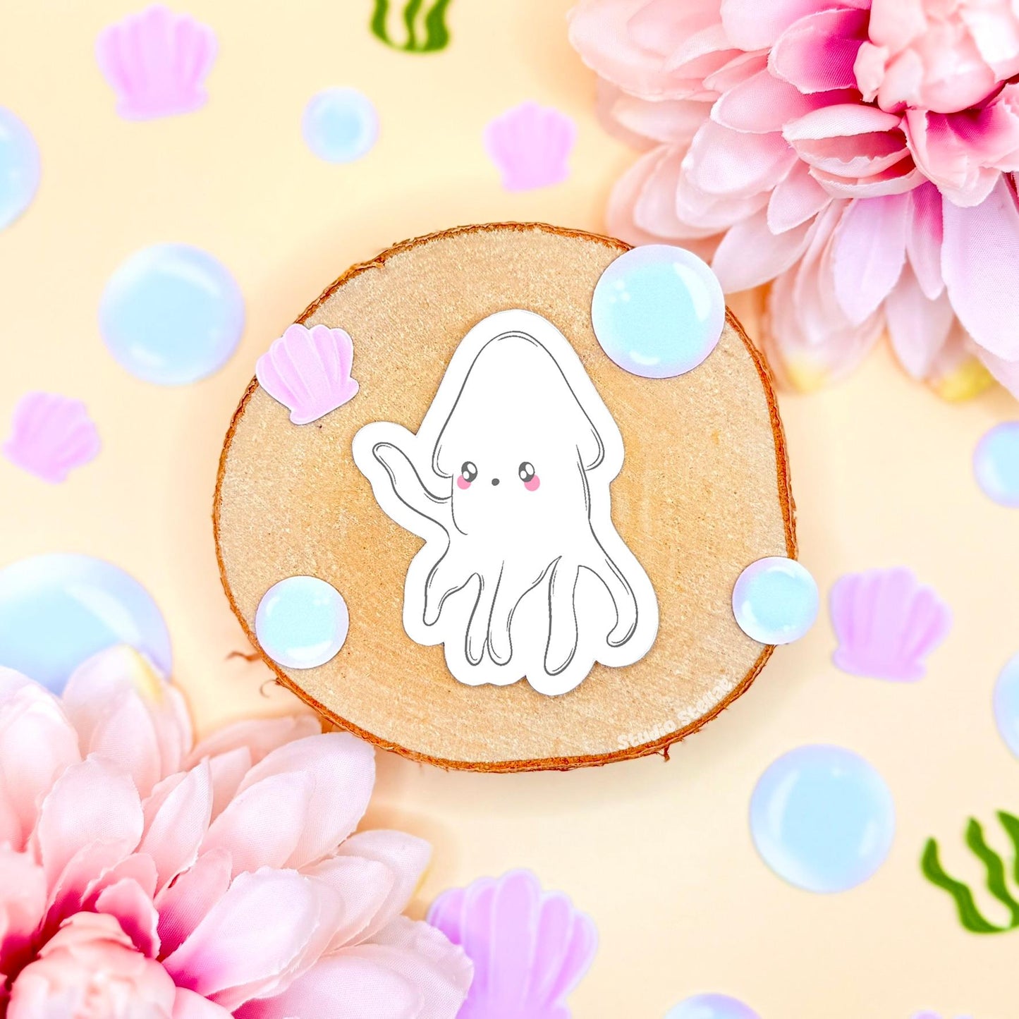 Close-up of the white chibi squid sticker styled on a pastel background with flowers and soft bubbles, highlighting its rounded shape, gentle expression and soft kawaii aesthetic. The matte laminated surface keeps colors vibrant and protects from scratches and water. A sweet ocean animal decal perfect for decorating laptops, planners, journals and water bottles with cozy sea life vibes.