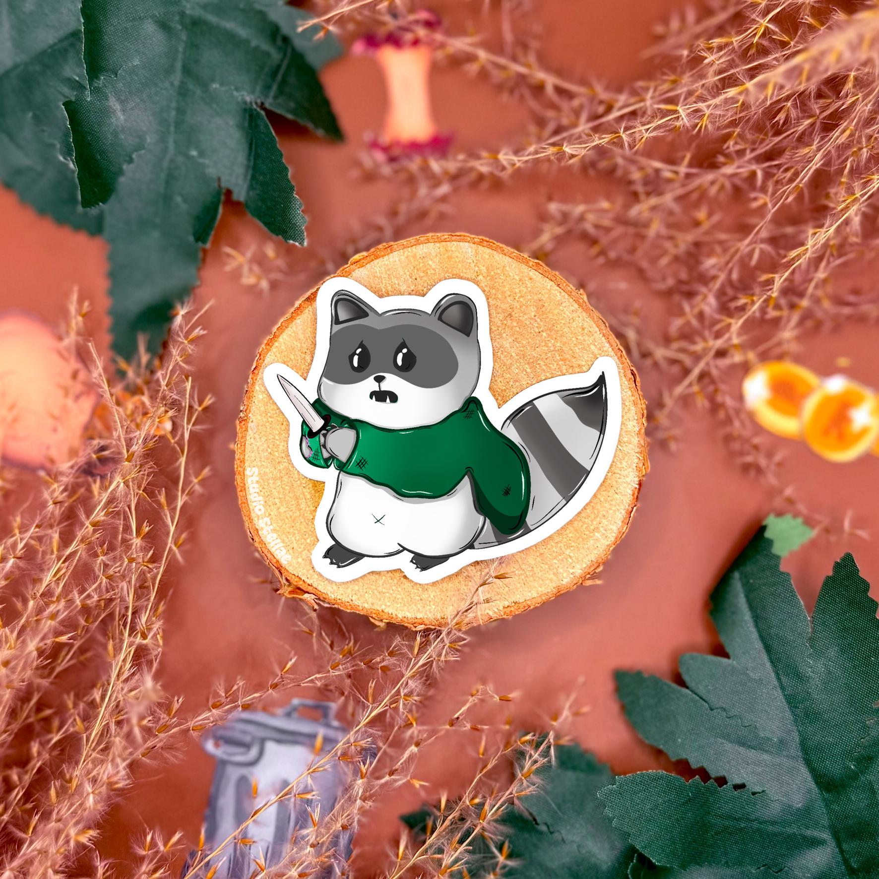 Detailed view of a rogue raccoon sticker posed with fantasy gear on a styled tabletop, emphasizing costume elements, soft shading, and handmade illustration style. This image showcases the character personality within the DnD raccoon sticker set and helps customers see scale and finish. Perfect for tabletop RPG fans looking to decorate gaming accessories or planners with cute fantasy animal art.