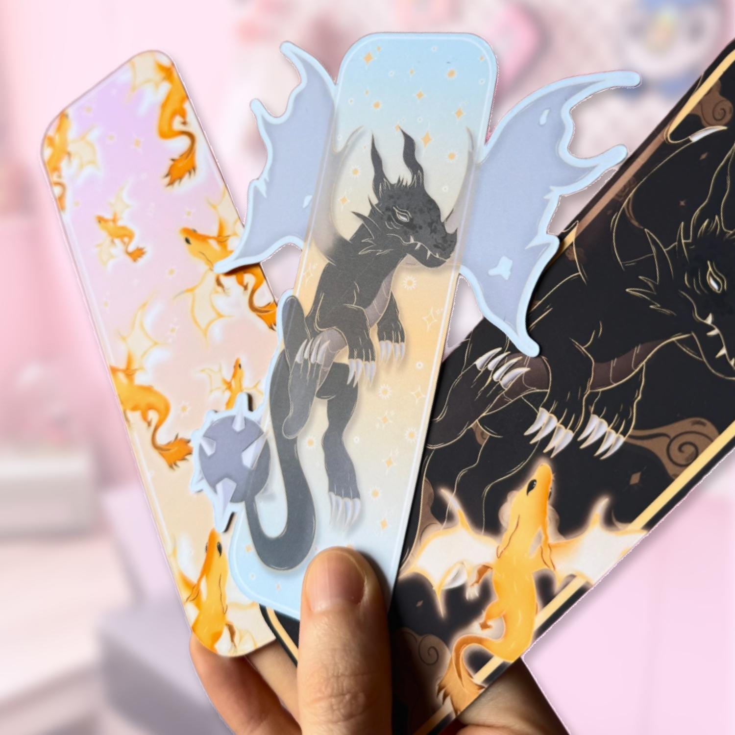 Close-up of the bookmarks wrapped in soft, semi-transparent paper with a delicate dragon print, held gently in hand. The designs underneath are partially visible, creating a layered and slightly diffused look. Warm lighting enhances the cozy and handmade feel, focusing on packaging texture, material, and the overall presentation of the bundle as a thoughtful gift item.