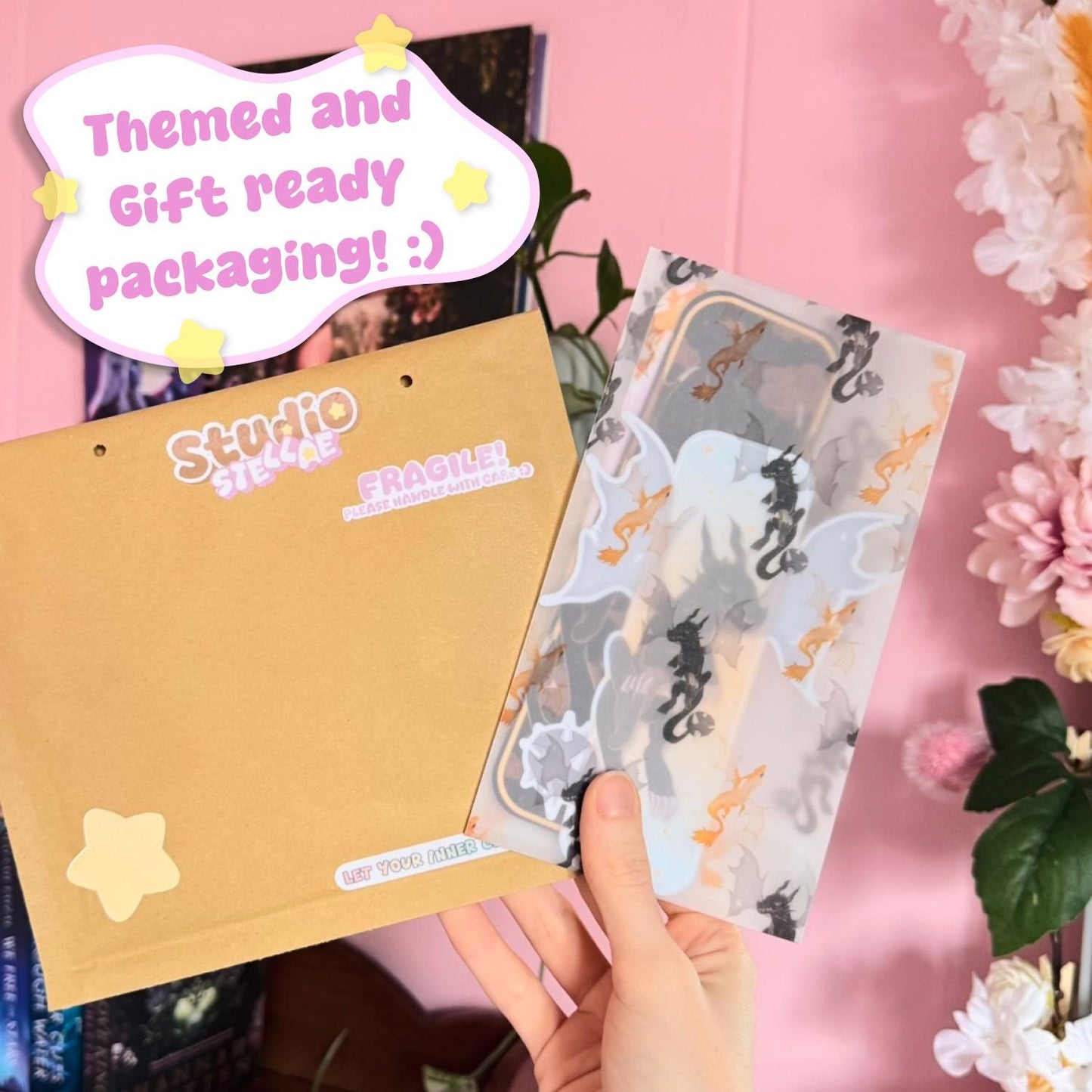 Hand holding the bookmark set partially inside a kraft envelope, paired with themed semi-transparent wrapping paper featuring a subtle dragon pattern. A small card indicating gift-ready packaging is visible, adding context to the presentation. This lifestyle shot highlights how the product arrives, emphasizing a cozy, ready-to-gift experience suitable for book lovers and stationery fans.